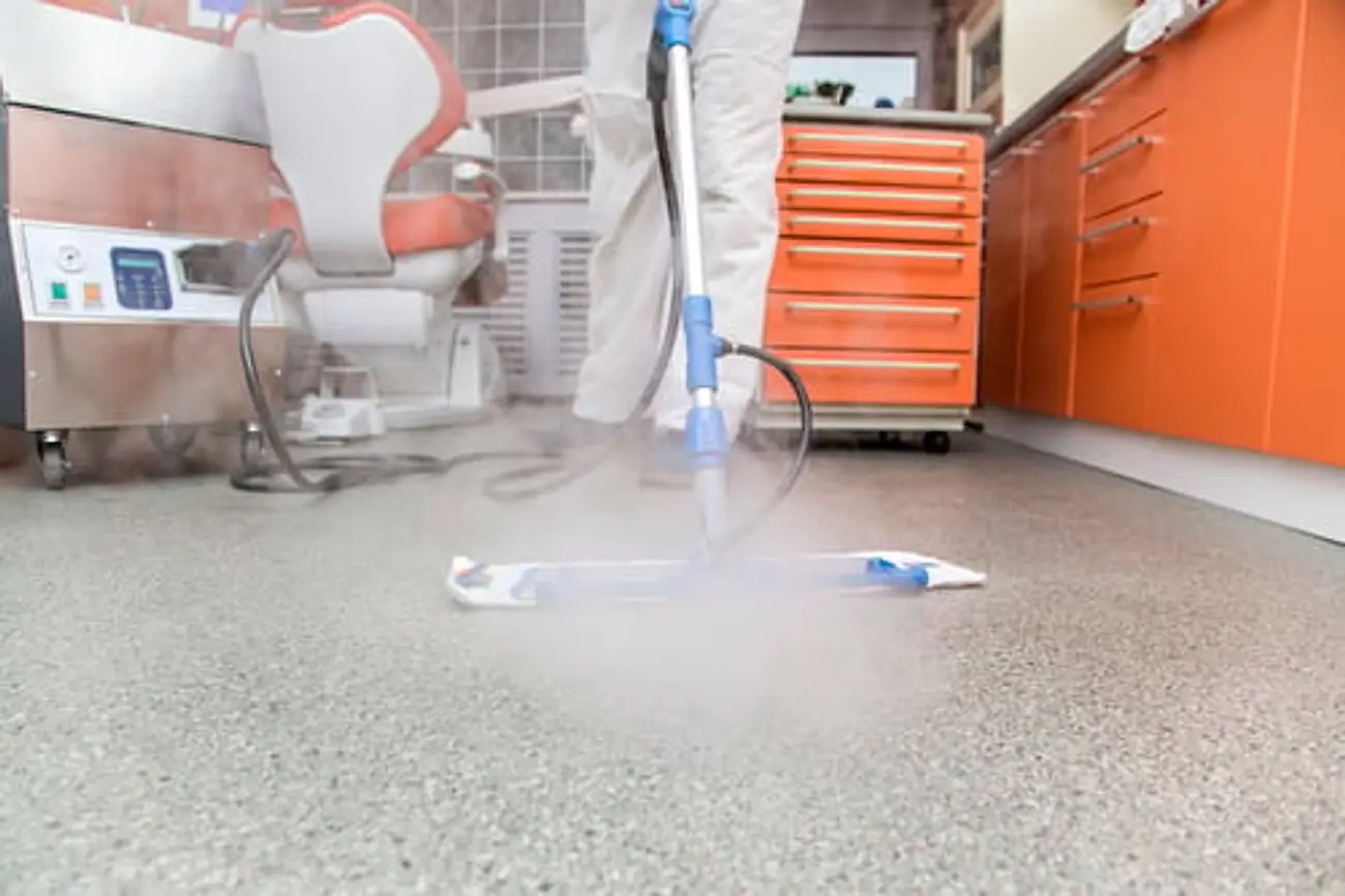 Technician in a protective suit disinfecting a dental operatory floor
